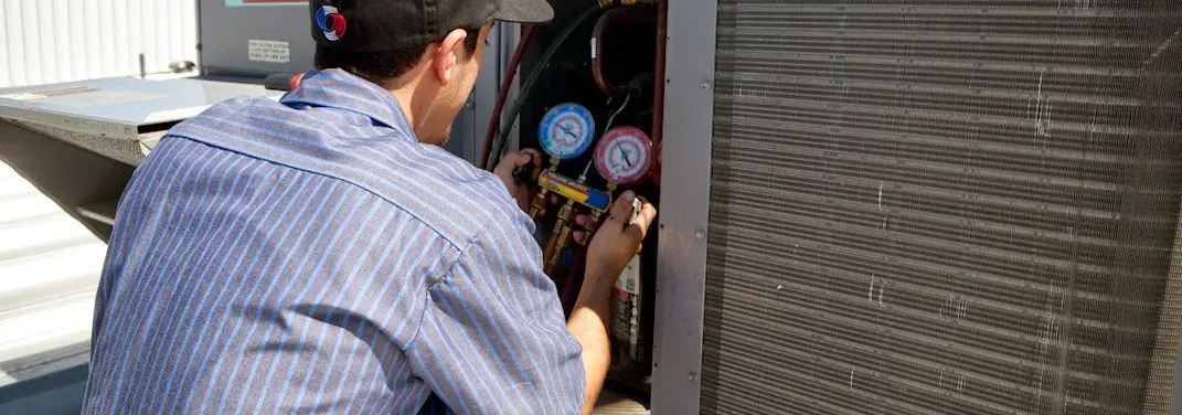 HVAC technician servicing a condenser unit in East Lampeter